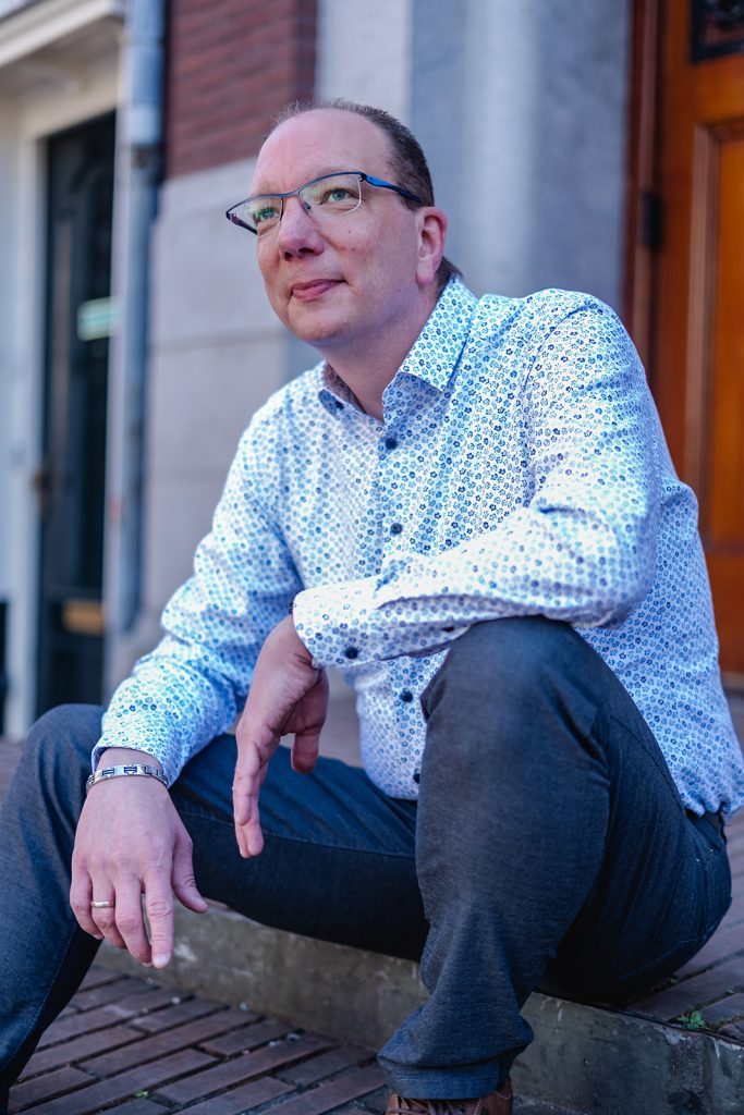 Edwin kijkt voor zich uit terwijl hij wacht op de stoep voor de deur van een oud huis